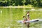 Young woman with school girl paddling on sup board on a lake. Active family on modern trendy stand up paddle board