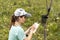 Young woman scientist zoologist writing down data from trap camera to notepad, observing wild animals in taiga forest, monitoring