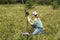 Young woman scientist zoologist writing down data from trap camera to notepad, observing wild animals in taiga forest, monitoring