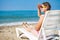 Young woman on sea beach sits on deckchair and looks into distance. girl in summer tropical resort relaxes on beach