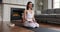 Young woman seated on knees do meditation practice at home