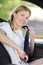 young woman securing seatbelt in car