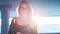 young woman seductively moves towards the camera, and covers her shoulders with leather jacket in a bright light