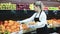 Young woman selling fresh oranges and fruits on the supermarket