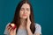 Young woman with sensitive teeth and apple on color background