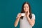 Young woman with sensitive teeth and cup of hot coffee on color background