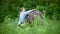 Young woman sets the saddle on the horse in the meadow