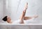 Young woman shaving legs while having bath