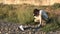 Young woman shooting a dead seagull photo by the shore