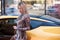 Young woman with shopping bag near the yellow super car, outdoors