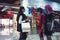 Young woman in shopping centre standing near the shop window and looking at two mannequins in dresses and wigs. Trendy attractive