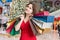 Young woman is shopping gifts for Christmas and holds many colorful bags