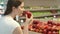 Young woman shopping in grocery store for healthy food. Vegan girl choosing fresh red apples