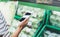 Young woman shopping healthy food in supermarket blur background. Female hands buy products cabagge using smart phone in store