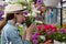 Young woman shopping in an outdoors fresh urban flowers market, buying and picking from a large variety of colorful floral