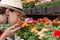 Young woman shopping in an outdoors fresh urban flowers market, buying and picking from a large variety of colorful floral