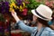 Young woman shopping in an outdoors fresh urban flowers market, buying and picking from a large variety of colorful floral