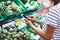 Young woman shopping purchase healthy food in supermarket blur background. Close up view girl buy products using smartphone in sto