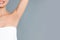 Young woman showing hairless armpit after epilation procedure on grey background. Space for text