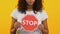 Young woman showing stop sign on yellow background, problem warning, restriction
