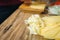 Young woman shredding cheese on a wooden table in kitchen