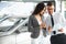 Young Woman Signing Documents at Car Dealership with Salesman