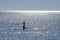 Young woman in silhouette practices stand up paddleboarding