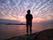 Young woman silhouette standing on beach looking at the dramatic sunrise sky view.