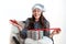 Young woman in a silver santa hat sitting on a chair and holding a gift box in her hands, isolated on a white background