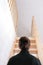 Young woman simple hairstyle back view by wooden stairs at home. Depression, loneliness and quarantine concept. Mental