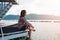 young woman sit alone on bridge has river, mountain, sky are background. image for travel, scenery, lonely, portrait, person, lan