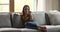 Young woman sit on sofa use smartphone talk by videocall