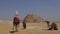 Young woman sits atop a camel in Egypt. Great Pyramids of Giza.