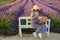 Young woman sits on the bench nestled in a vibrant lavender field