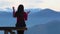 Young woman sits on bench outside and look at pictorial landscape with mountains