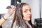 Young woman sits in a chair during process of dyeing hair and lo