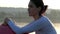 A young woman sits with a fitball on a lake bank