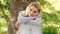 Young woman sits on a grass in a park hold laptop and smiles. Dreamy female student.