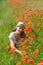 The young woman sits on a grass among red poppies