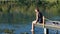 a young woman sits with her back to the camera on the pier and dangles her legs in the water