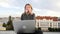 Young woman sits with laptop and listening music on headphones on the rooftop.