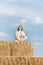Young woman sits in lotus position on huge haystack and meditates. Countryside holiday