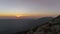 Young woman sits on mountain top or peak at sunset