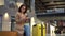 A young woman sits with a phone in her hands in a shopping center with a suitcase. Girl in pink coat.