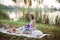 A young woman sits on a picnic in a park on the banks of a river