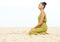 Young woman sitting alone and meditating at the beach