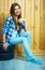 Young woman sitting on auto tires against wooden wall.