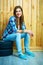 Young woman sitting on auto tires against wooden wall.