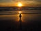 Young woman sitting on the beach, silhouette at sunset. Young woman practicing yoga outdoors. Harmony and meditation concept.