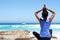 Young woman sitting at the beach in yoga pose